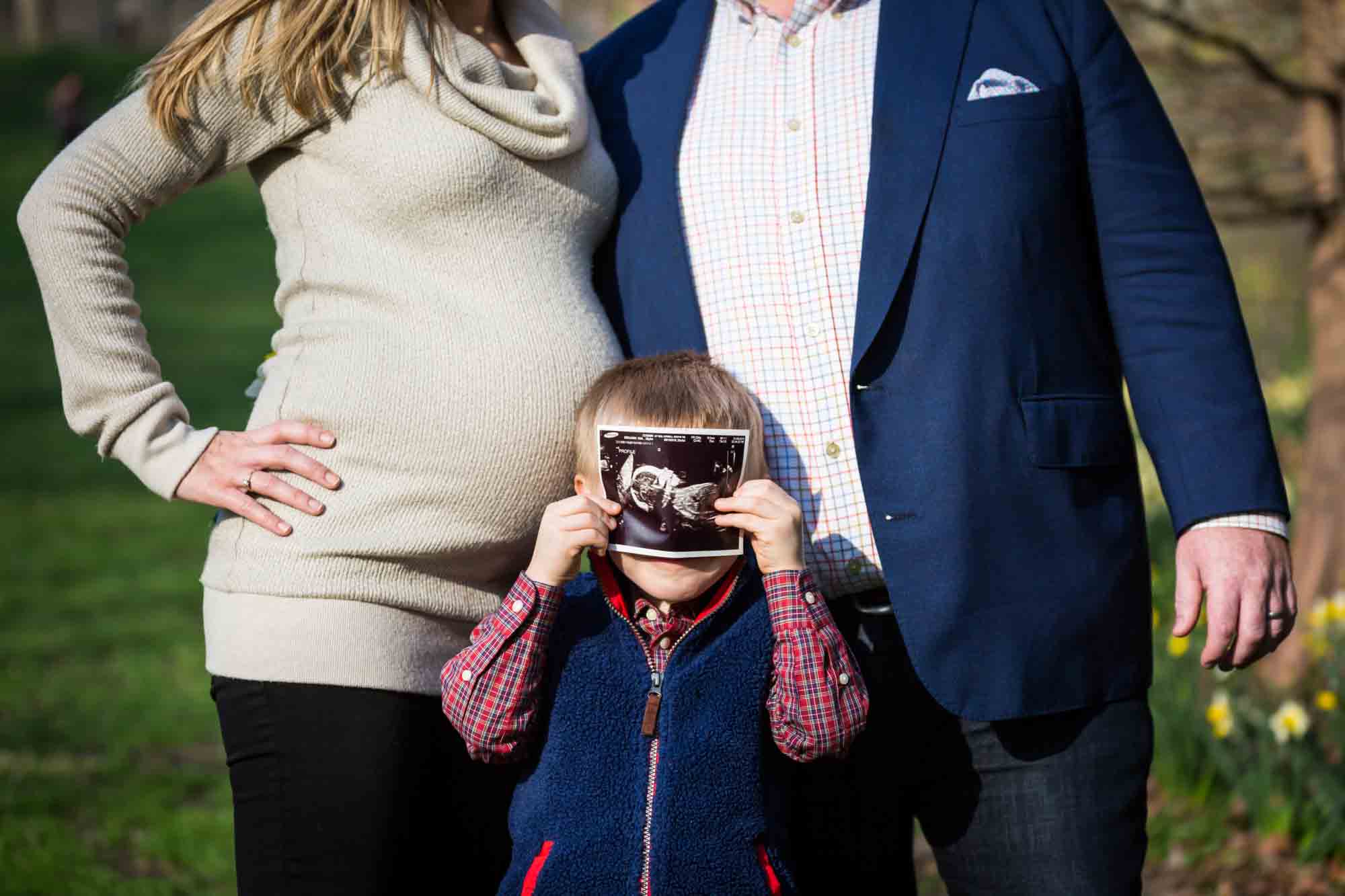 Family with child with sonogram photo for an article on the best family portrait poses