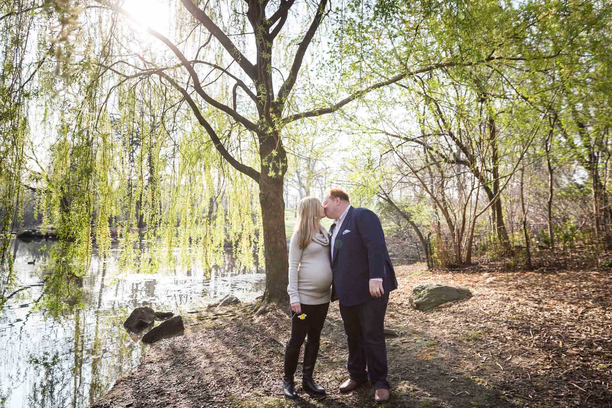 Parents kissing in park for an article on the best family portrait poses