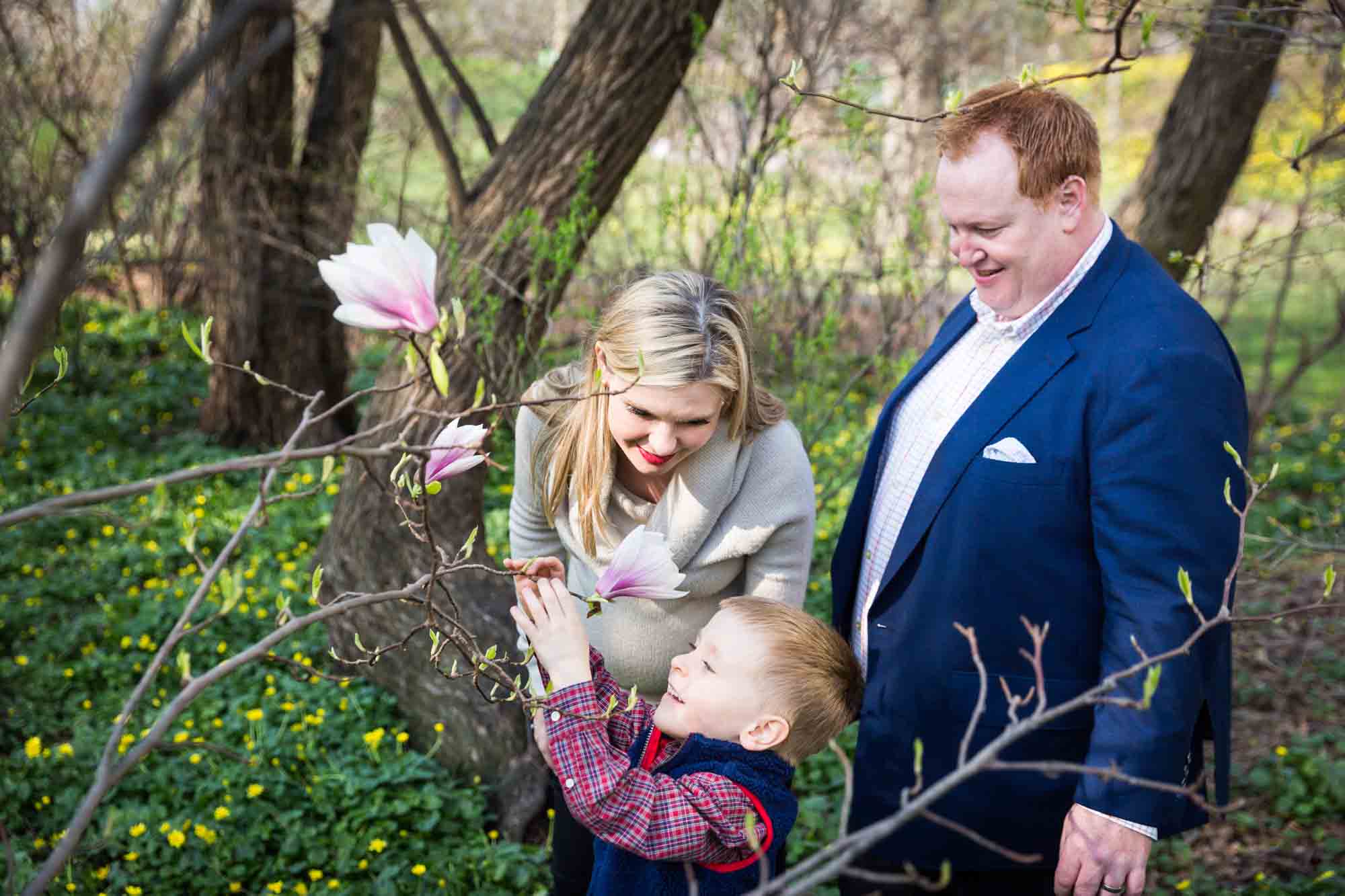 Parents and child smelling flower for an article on the best family portrait poses