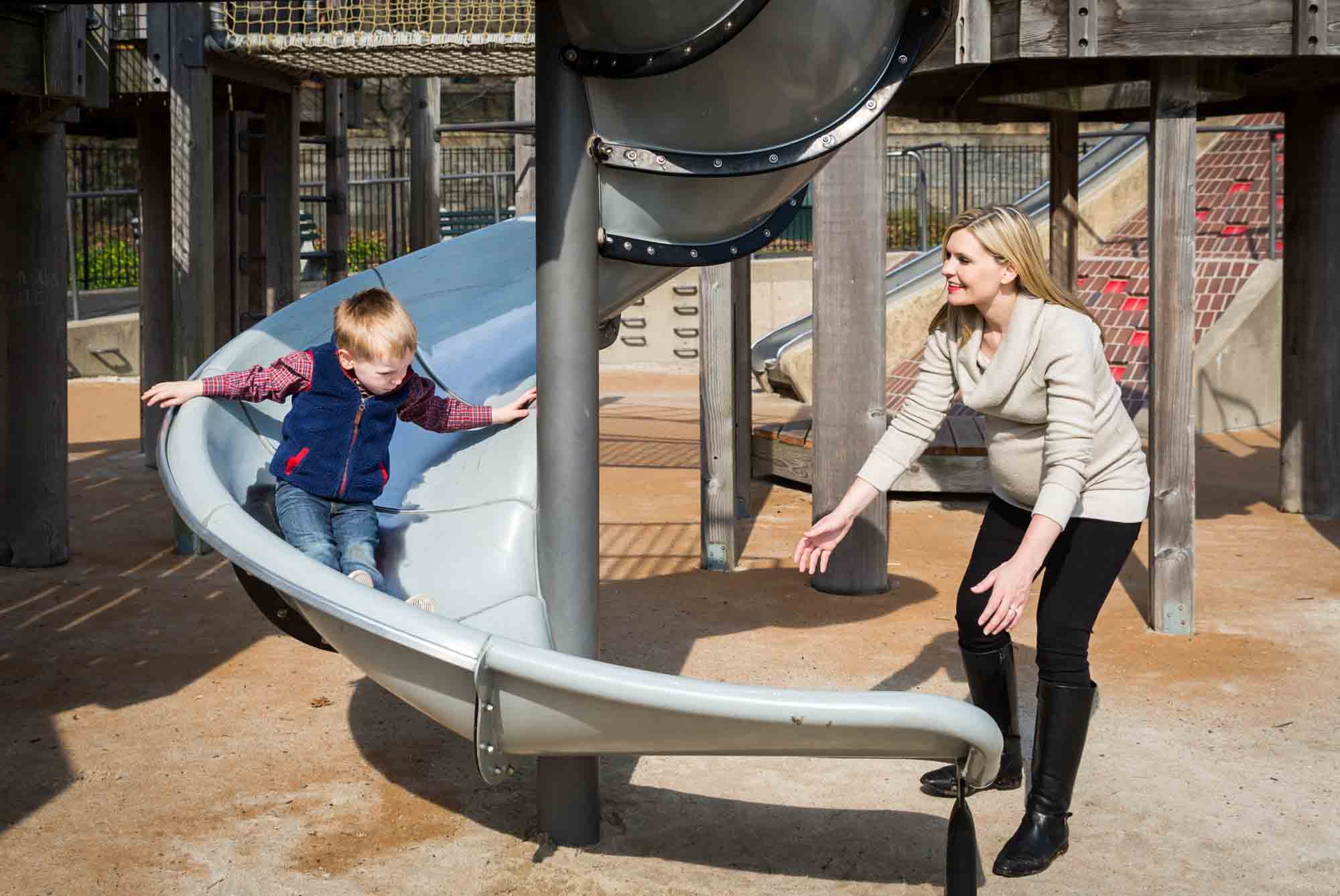 Mother with son going down slide for an article on the best family portrait poses