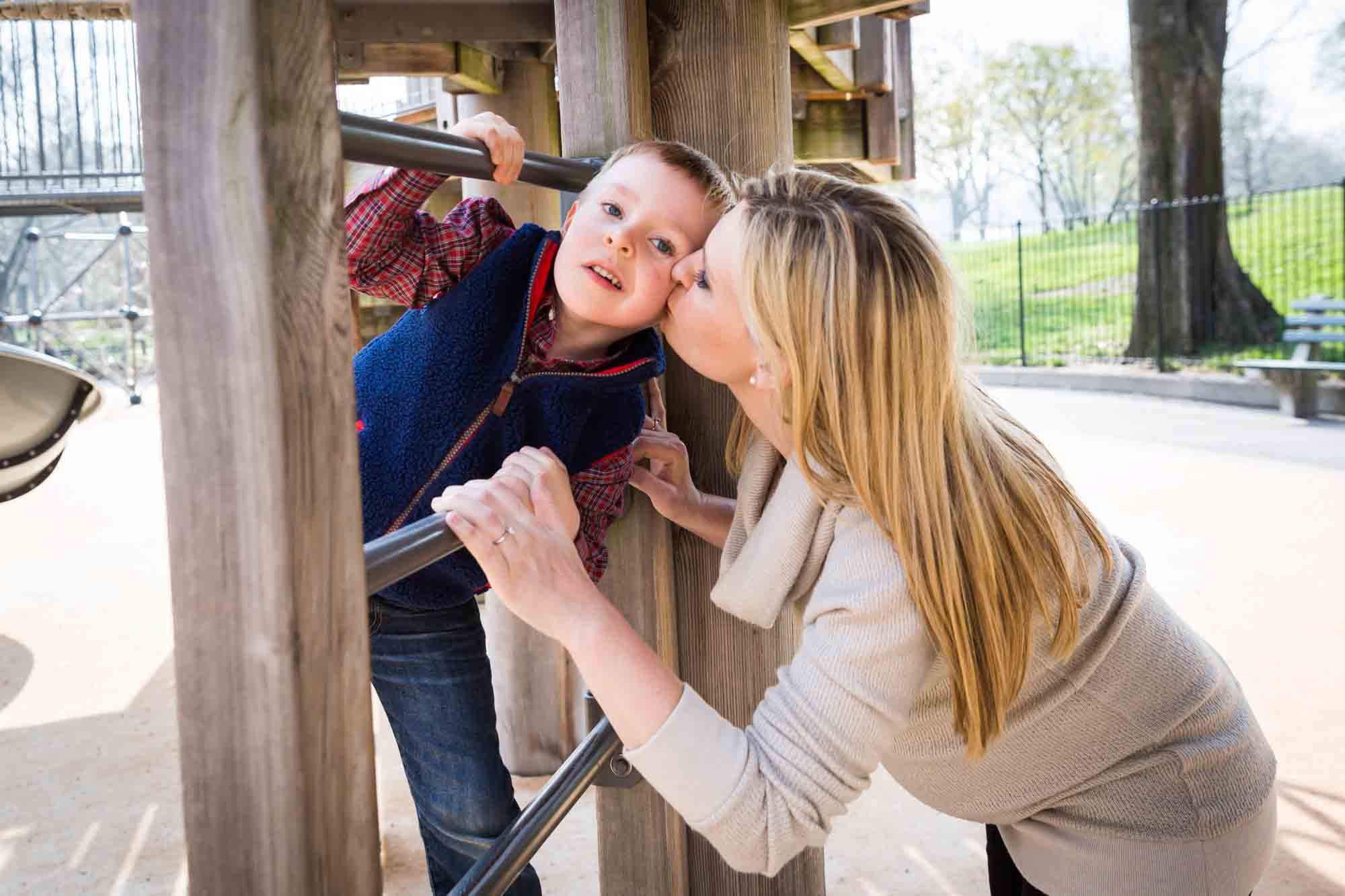 Mother kissing son on playground for an article on the best family portrait poses
