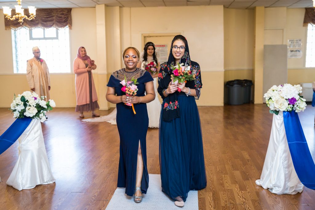 Two bridesmaids walking down aisle at Muslim wedding for an article on wedding photography timeline tips