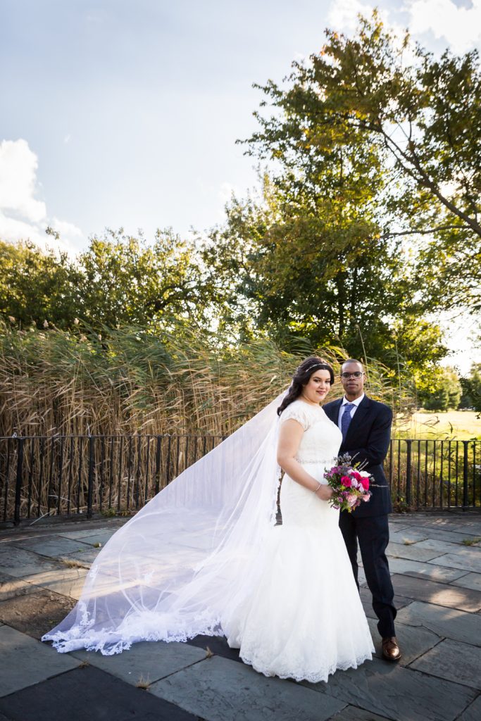 Portrait of bride with veil and groom in park