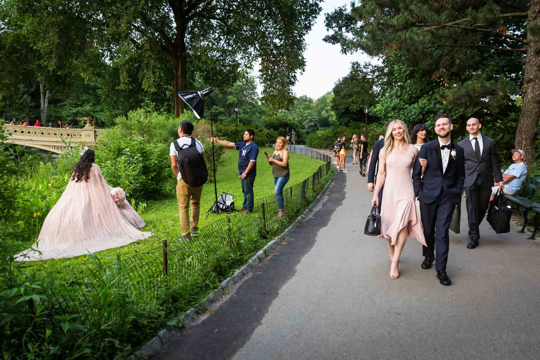 Wedding party walking past photo shoot for an article entitled, ‘Do you need a permit to get married in Central Park?’