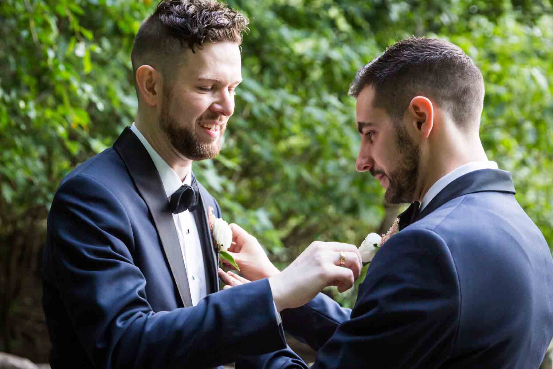 Grooms adjusting each others boutonnieres for an article entitled, ‘Do you need a permit to get married in Central Park?’