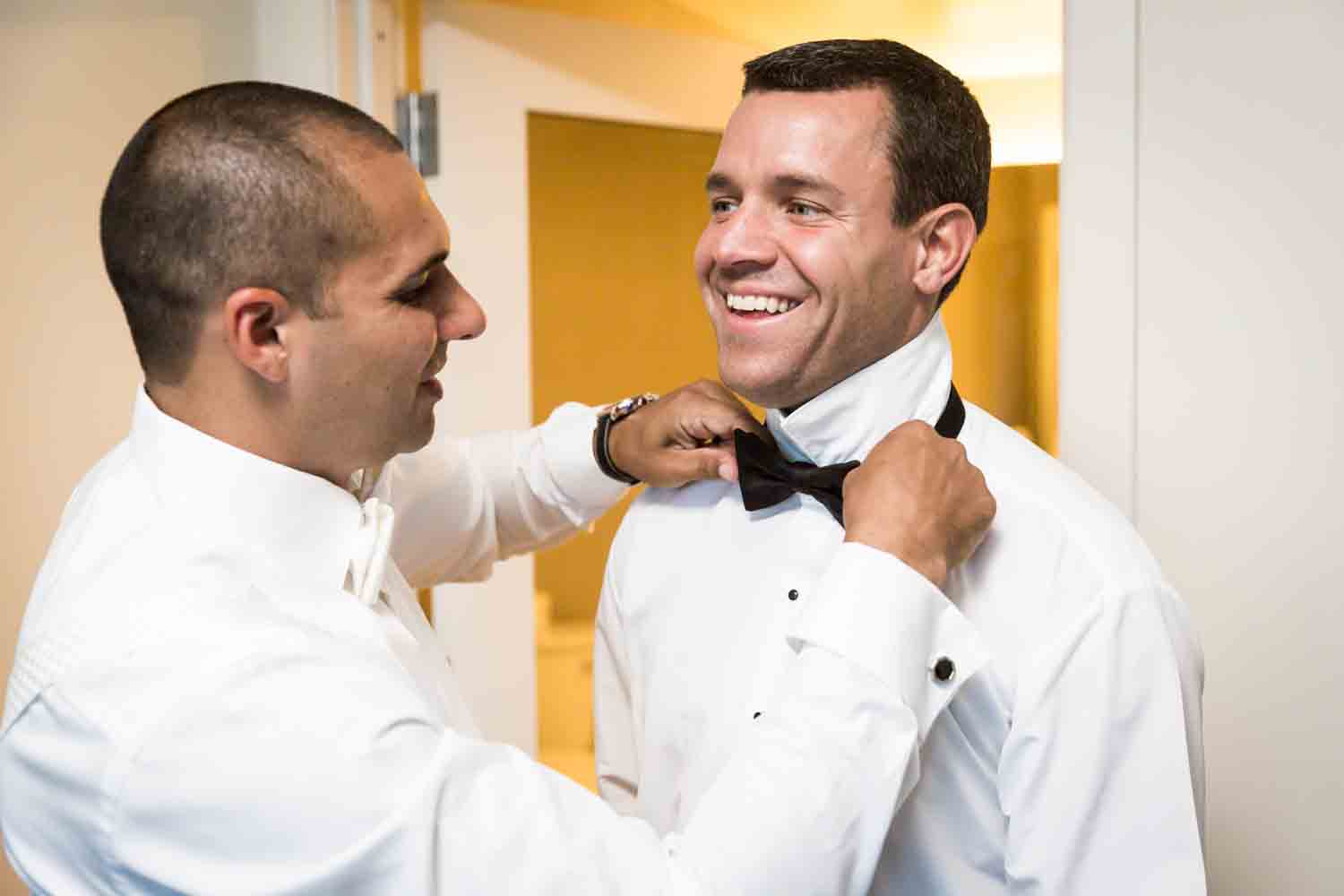 Groom adjusting groomsman's tie for an article on Bronx Zoo wedding venue updates