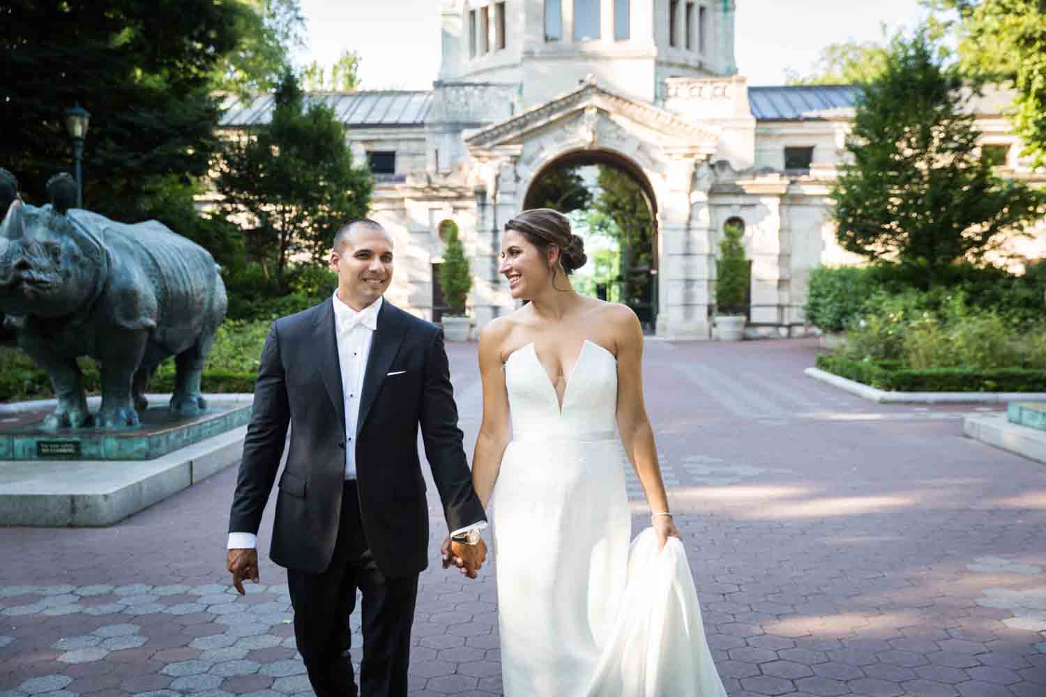 Bride and groom walking in front of Zoo Building for an article on Bronx Zoo wedding venue updates