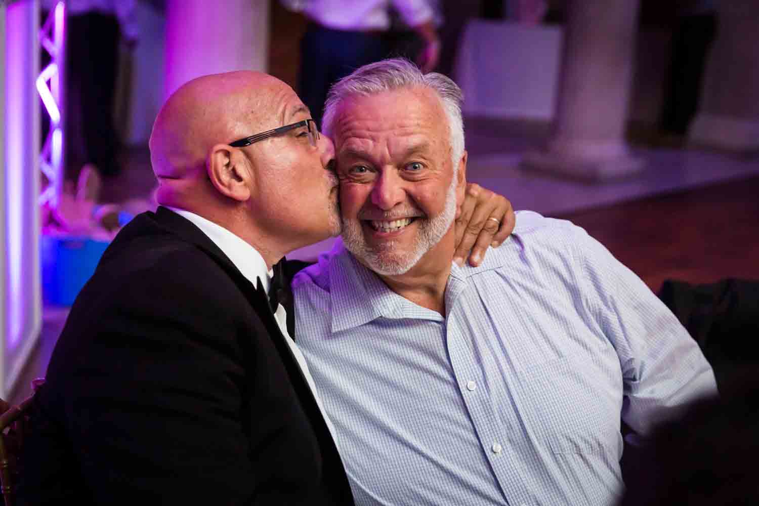 Father kissing guest on cheek for an article on Bronx Zoo wedding venue updates