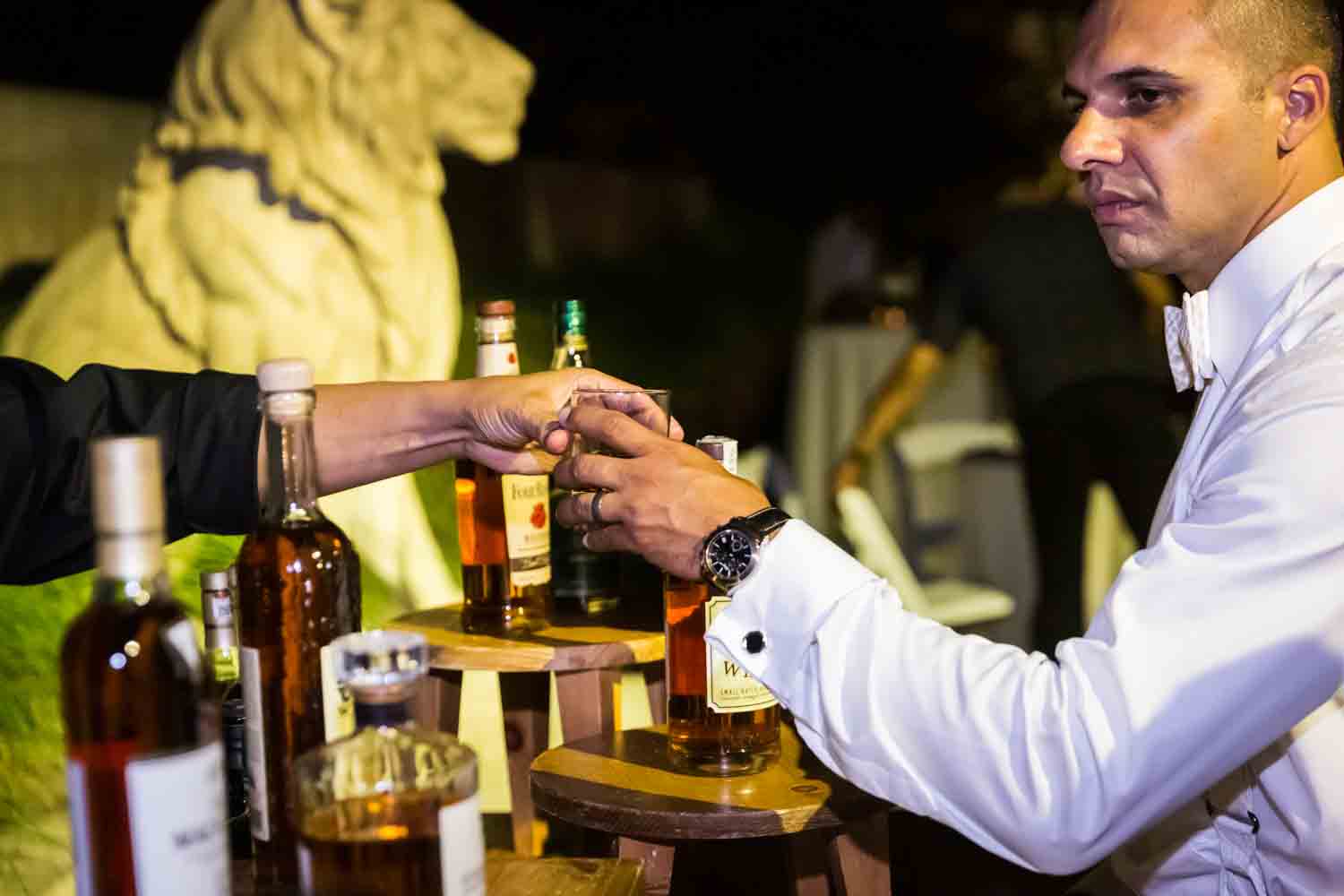 Groom sampling whiskey for an article on Bronx Zoo wedding venue updates