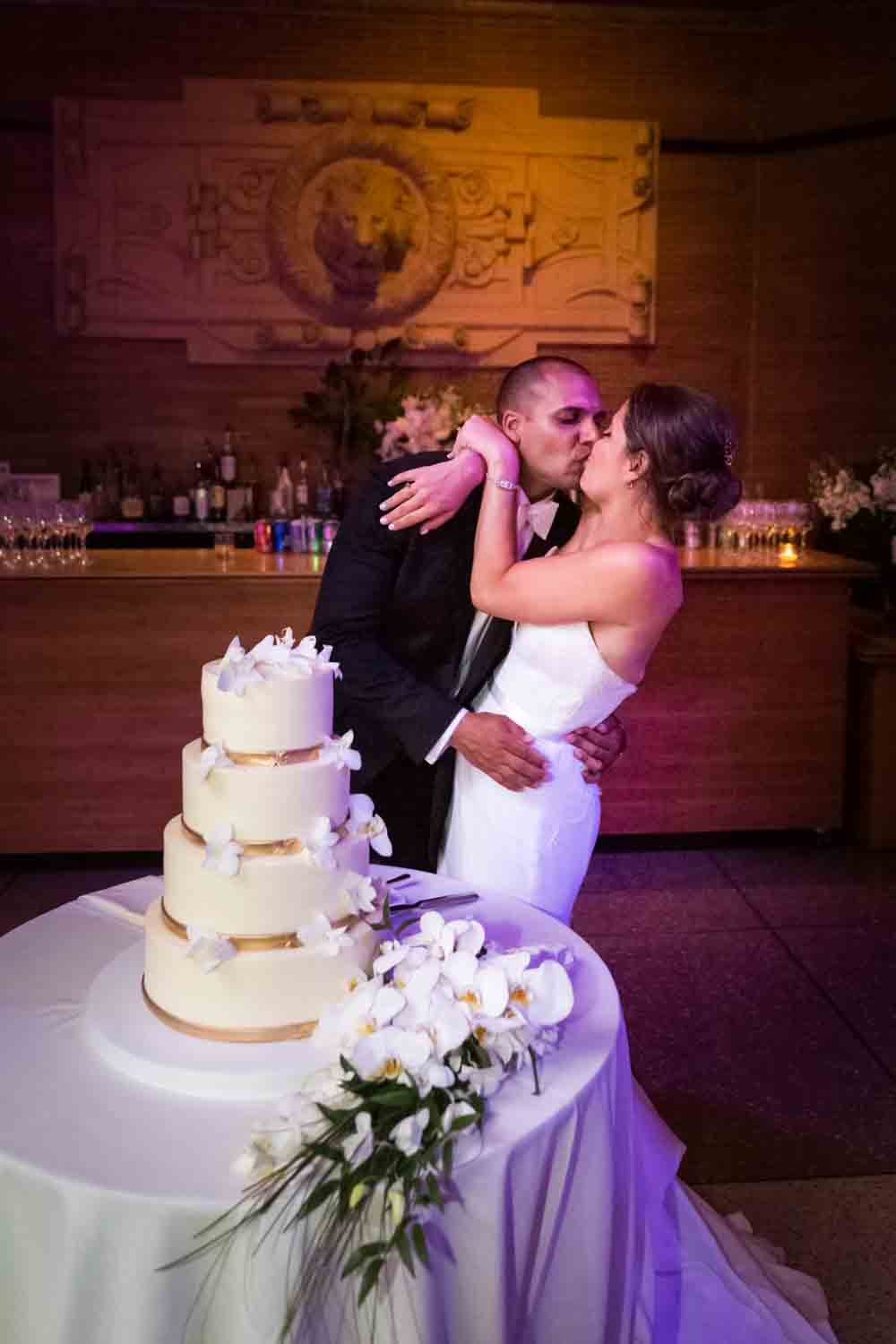 Bride and groom kissing by wedding cake for an article on Bronx Zoo wedding venue updates