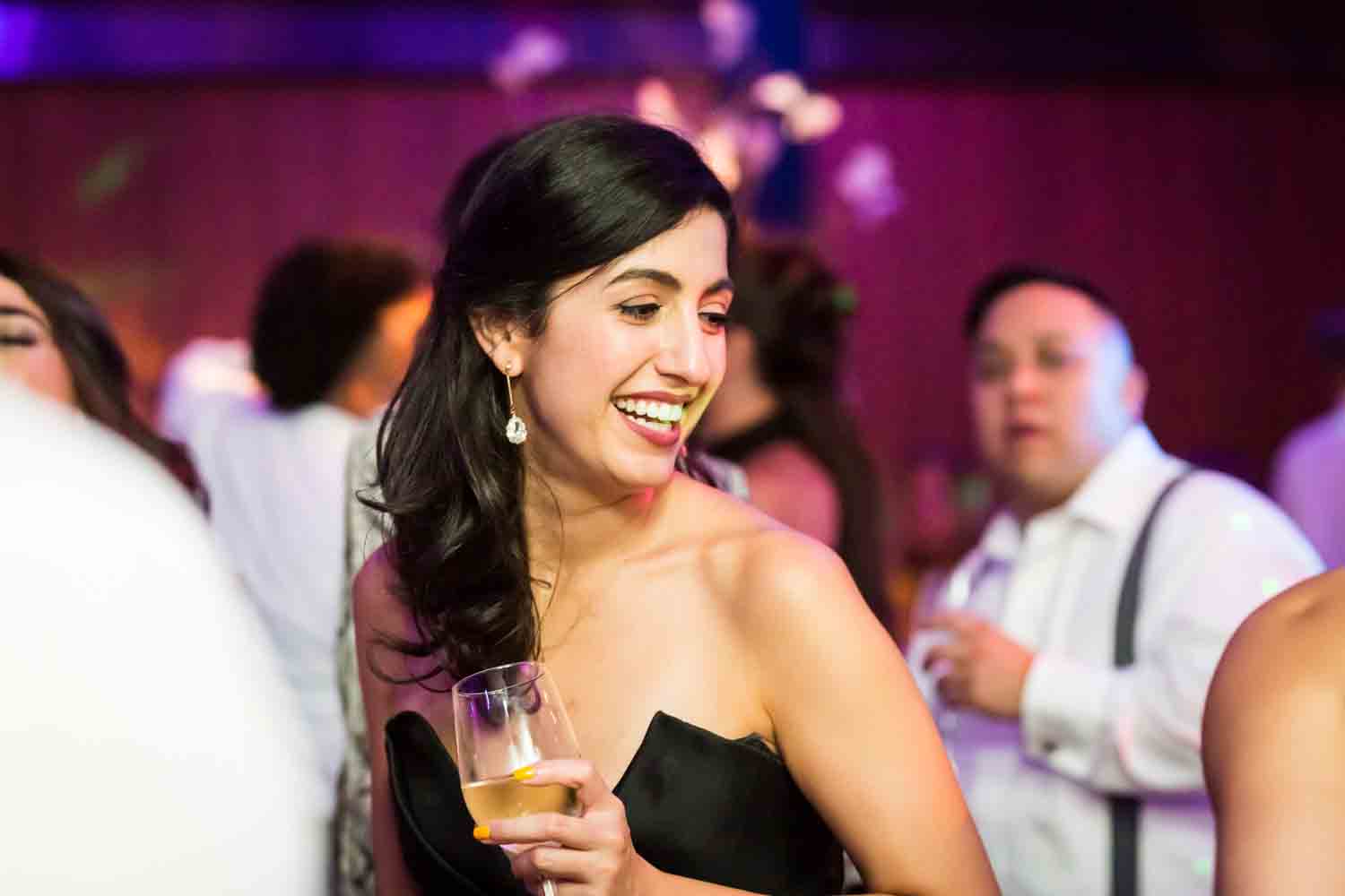 Guest with champagne glass dancing for an article on Bronx Zoo wedding venue updates