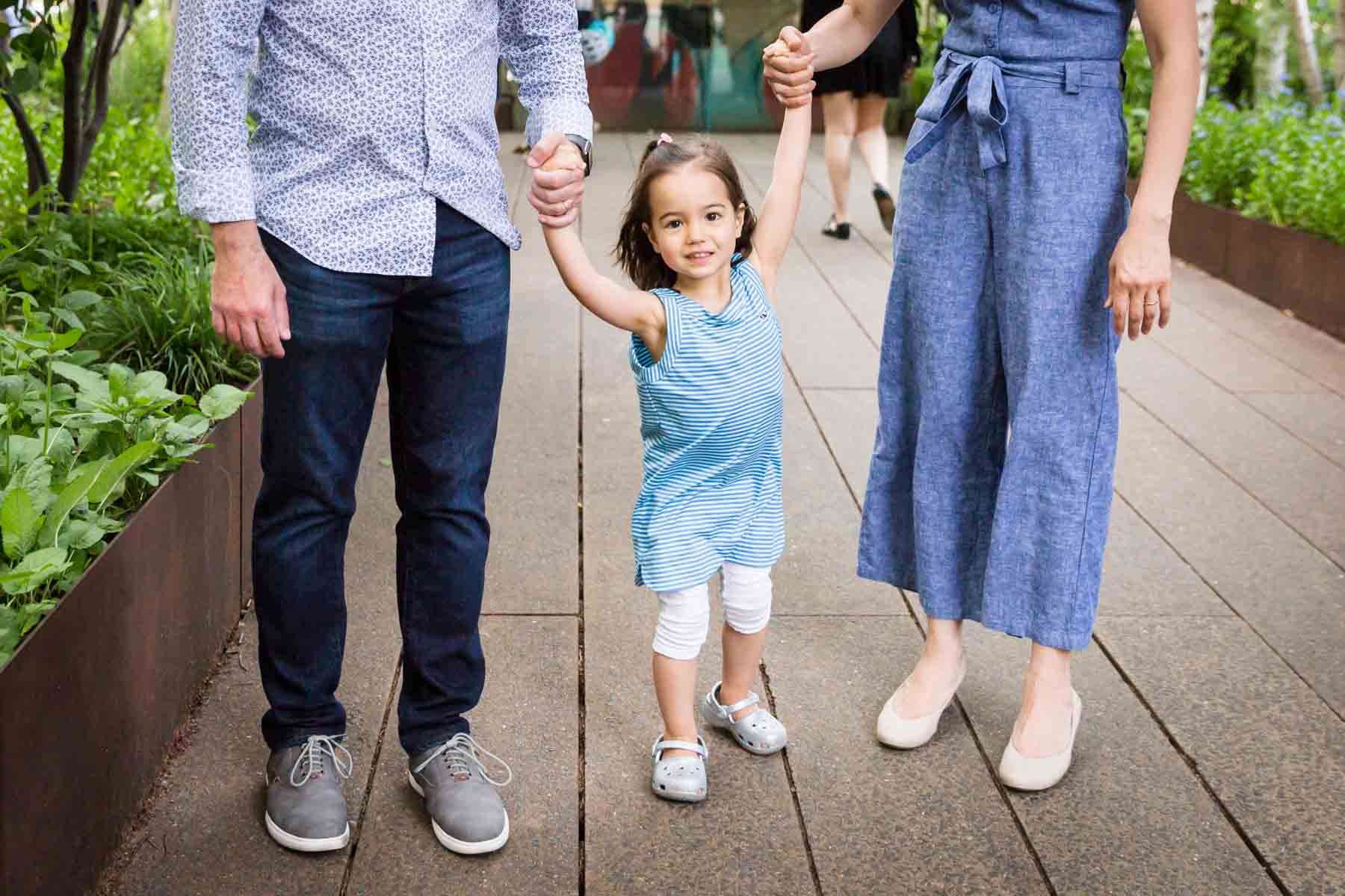 Little girl holding parents' hands for an article on High Line family portrait tips