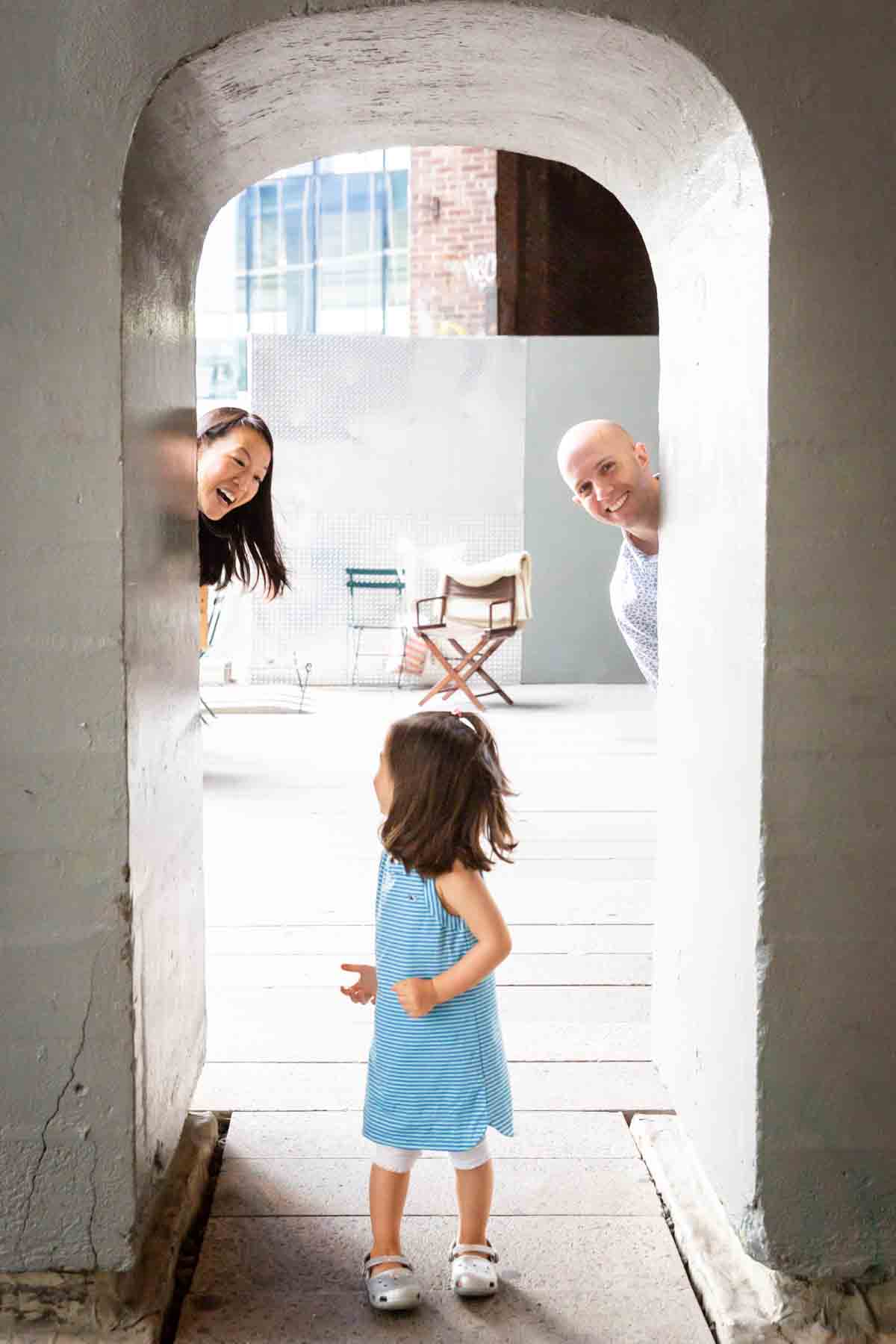 Parents playing peek-a-boo with little girl for an article on High Line family portrait tips