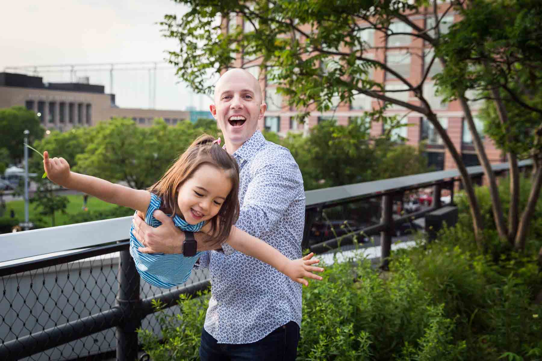 Father playing airplane with daughter for an article on High Line family portrait tips