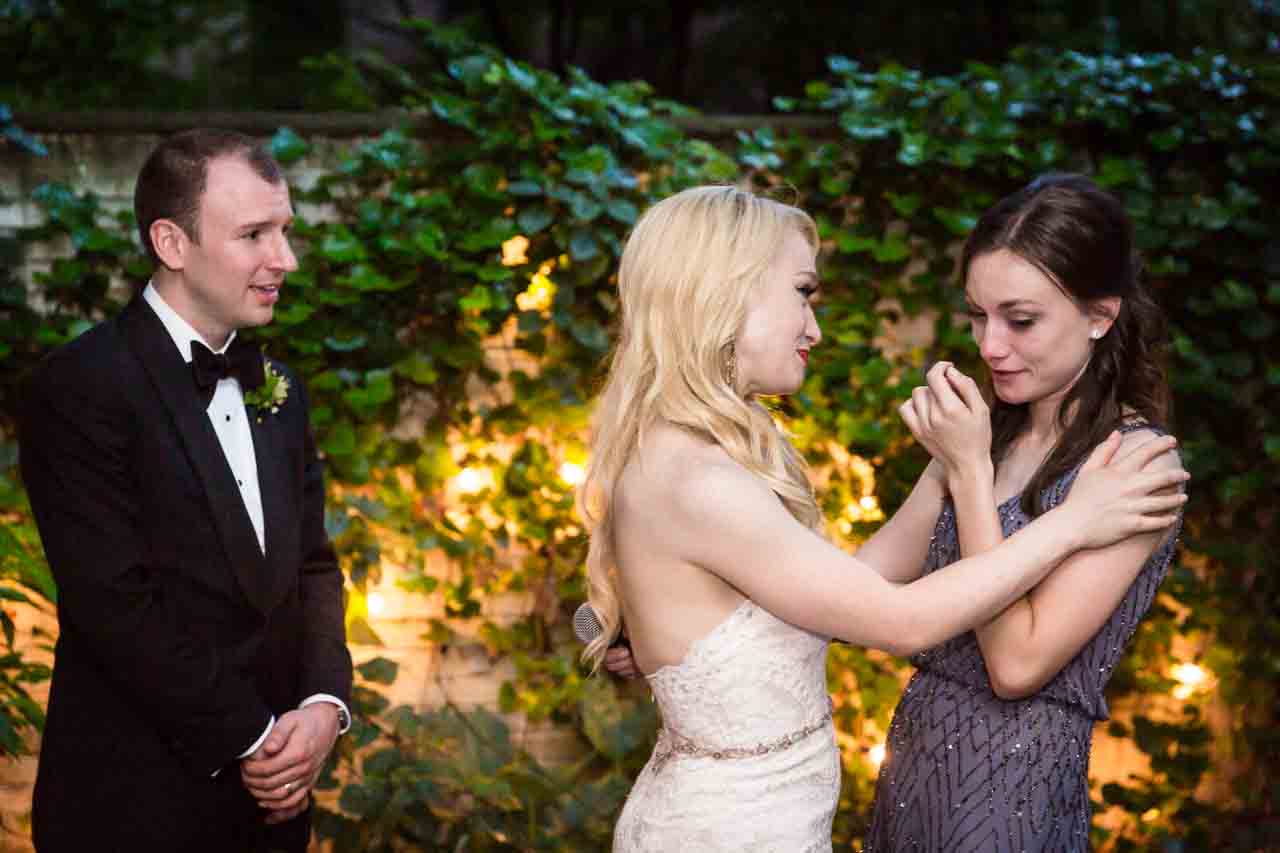 Bride comforting bridesmaid after toast at a Central Park Conservatory Garden wedding