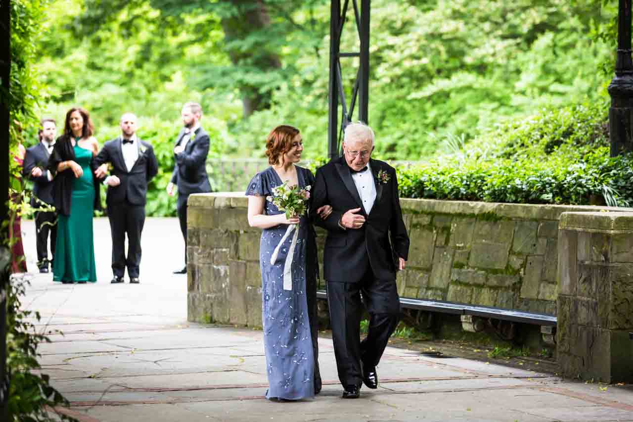 Bridesmaid and grandfather walking down aisle at a Central Park Conservatory Garden wedding