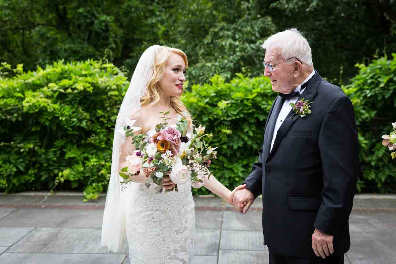 Bride and grandfather holding hands at a Central Park Conservatory Garden wedding
