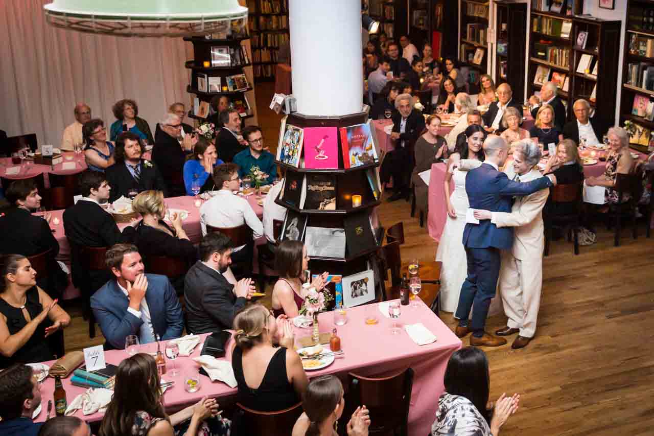 Bride and groom hugging speaker at reception