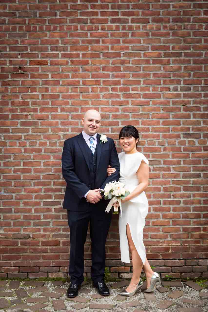 Bride and groom against brick wall