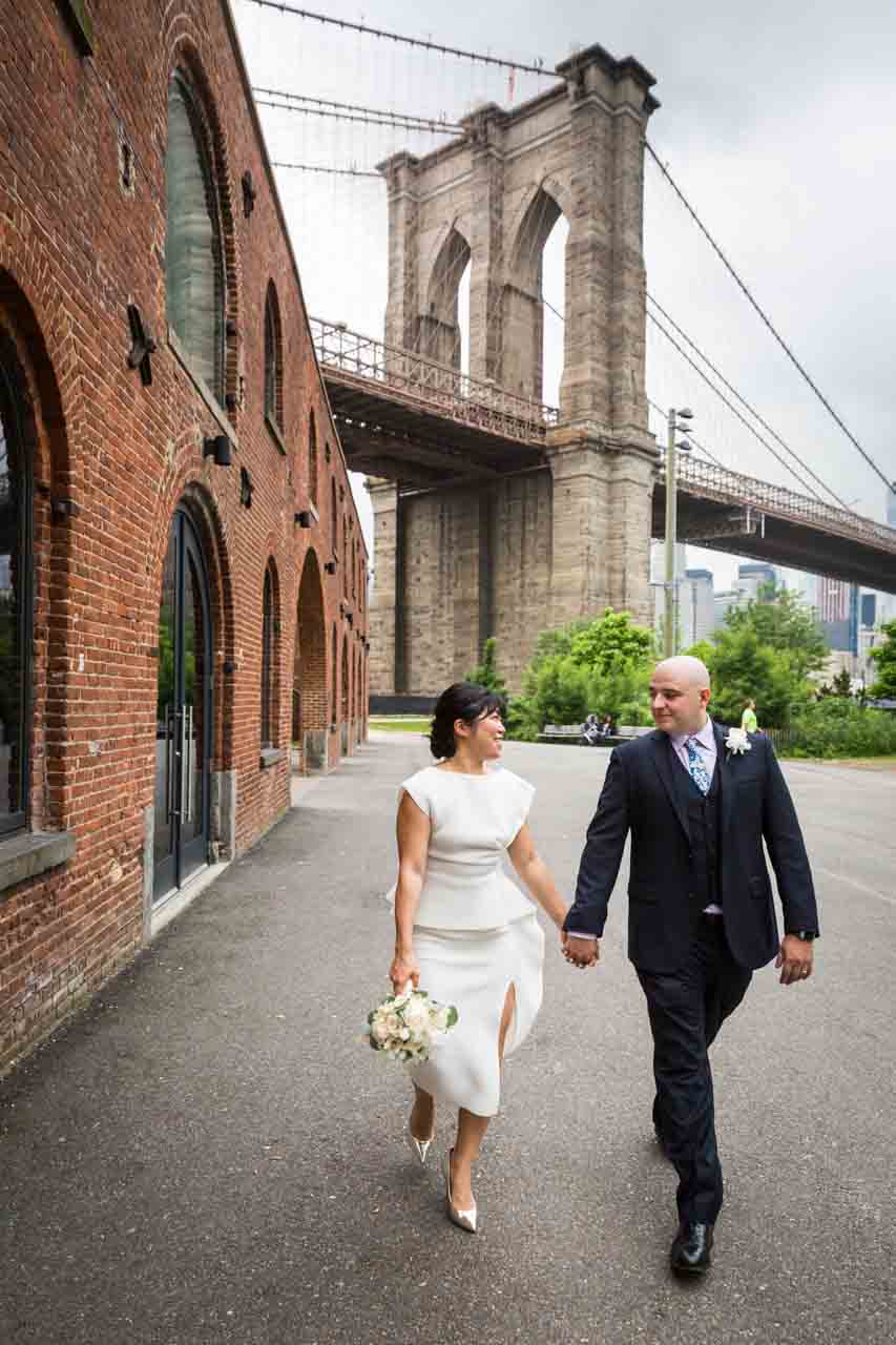 Bride and groom walking in front of Brooklyn Bridge