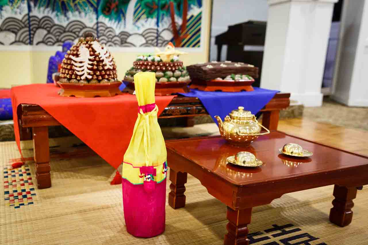 Tea set, jujubes, chestnuts, and rice wine bottle at traditional Korean pyebaek ceremony