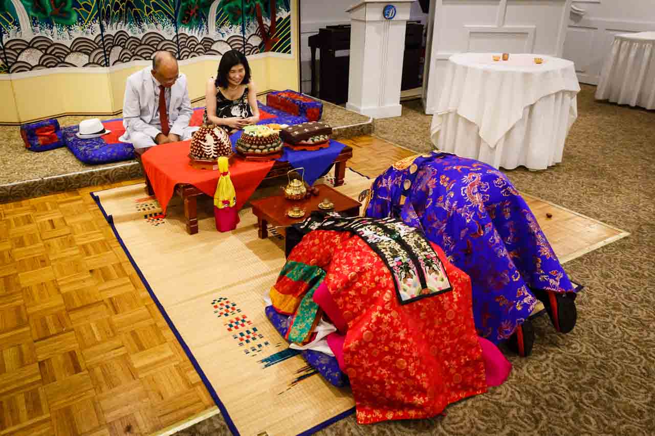 Bride and groom bowing to parents at traditional Korean pyebaek ceremony