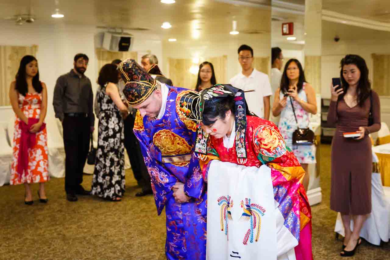 Bride and groom bowing at traditional Korean pyebaek ceremony 