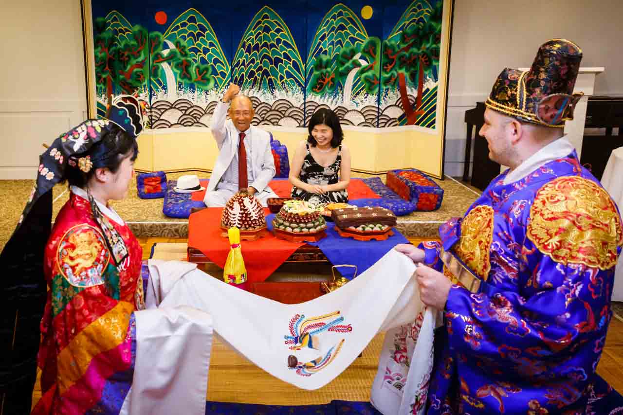 Bride and groom catching chestnuts at traditional Korean pyebaek ceremony