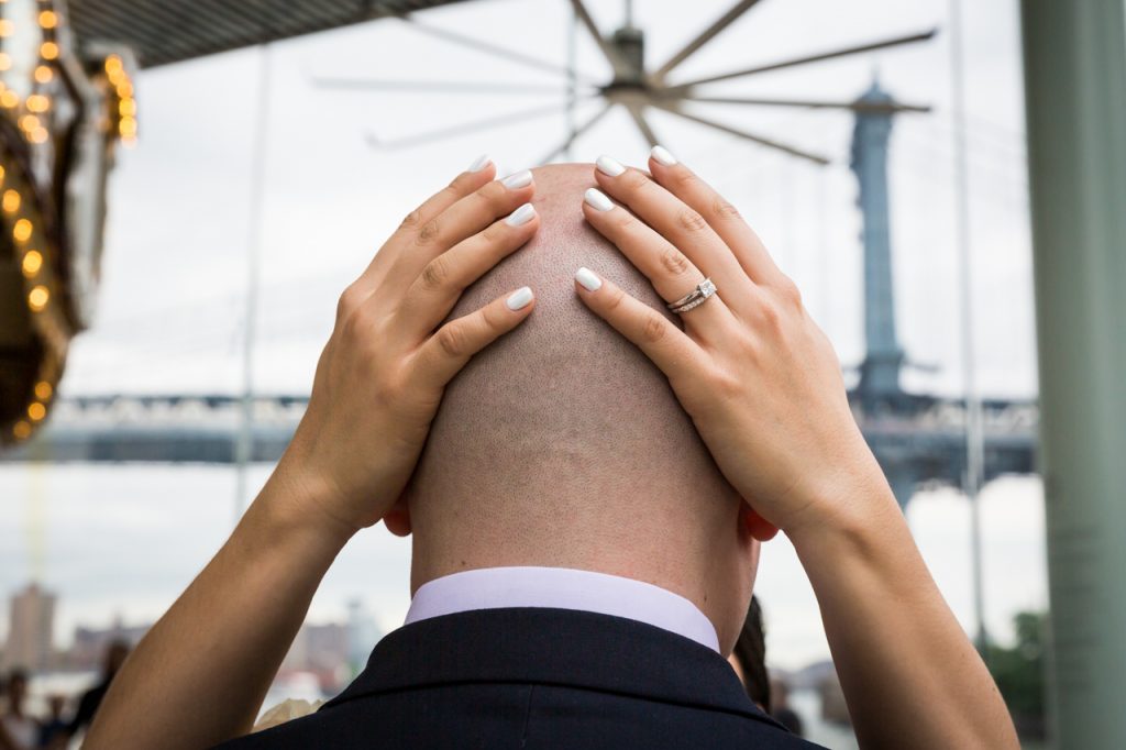 Bride's hands on groom's bald head