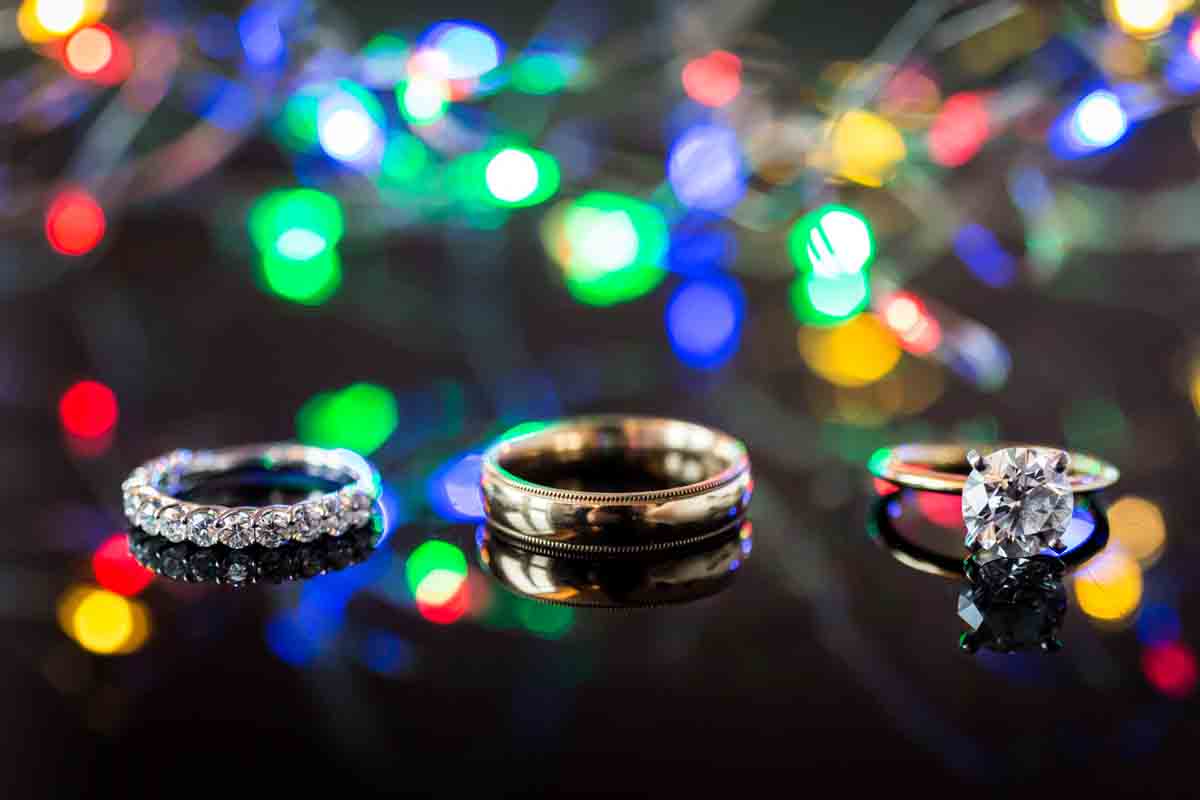 Wedding rings and engagement ring in front of colored lights