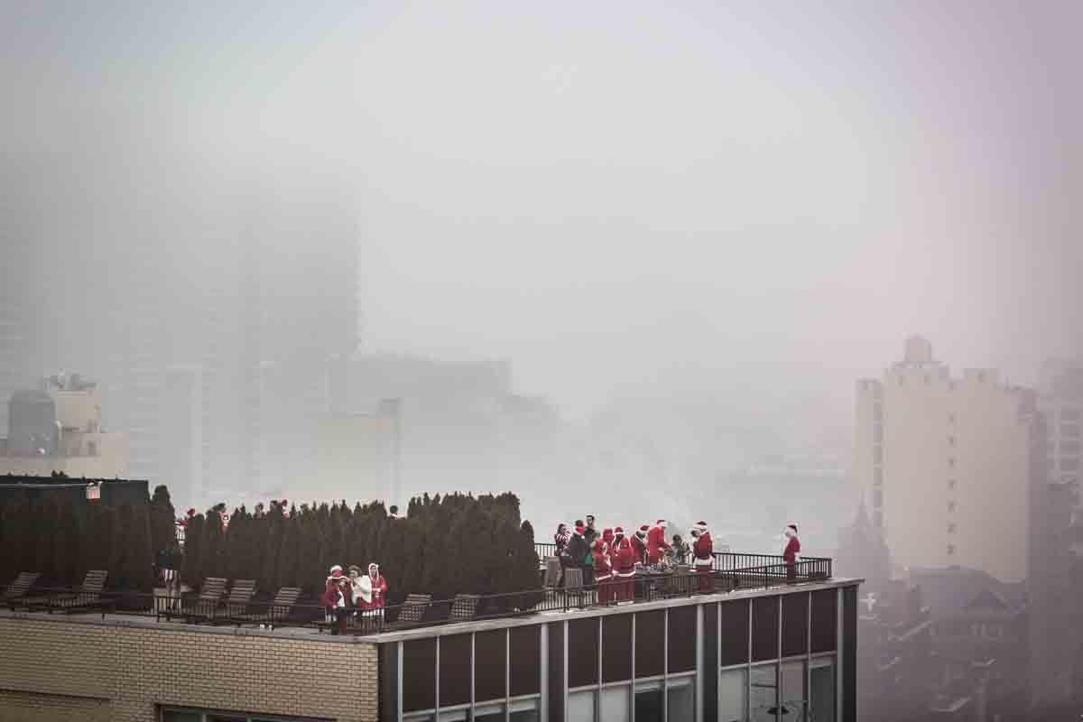 Group of SantaCon participants on hotel rooftop with fog