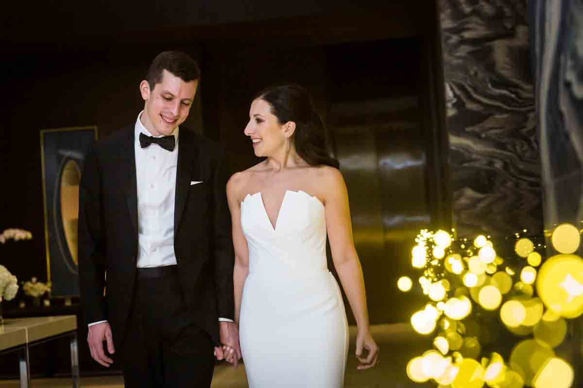 Bride and groom walking down hallway of Four Seasons Hotel New York Downtown