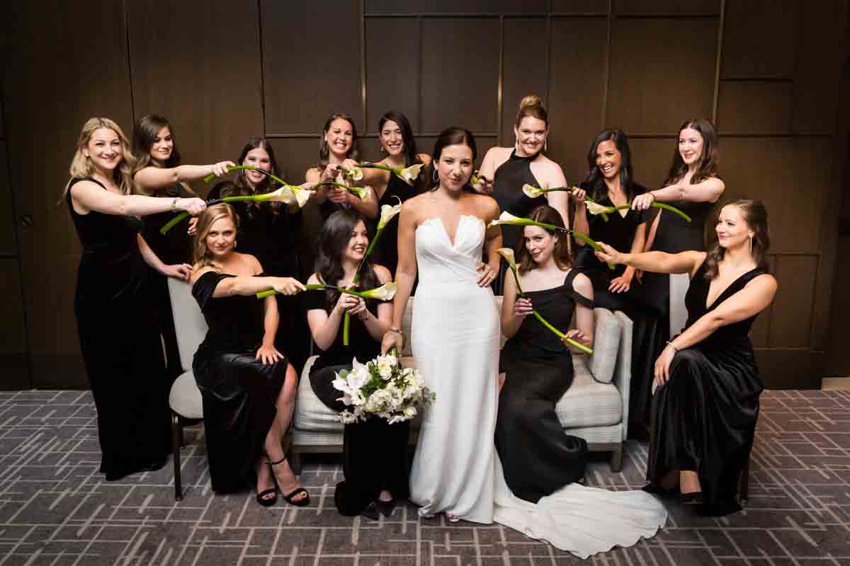 Funny portrait bridesmaids pointing bouquets at bride