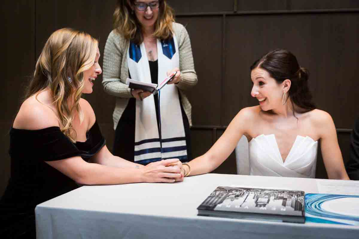 Bride and bridesmaid holding hands during ketubah signing at a Four Seasons Hotel New York Downtown wedding