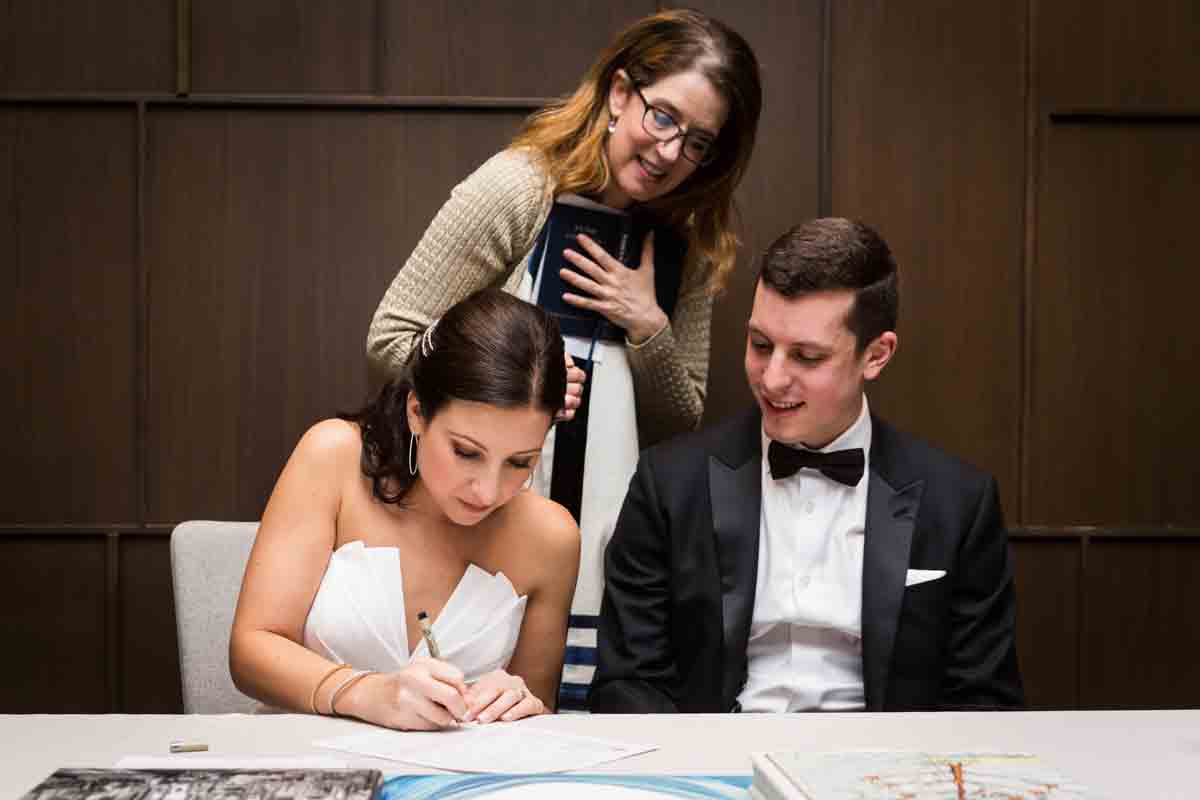 Cantor watching bride signing ketubah at a Four Seasons Hotel New York Downtown wedding