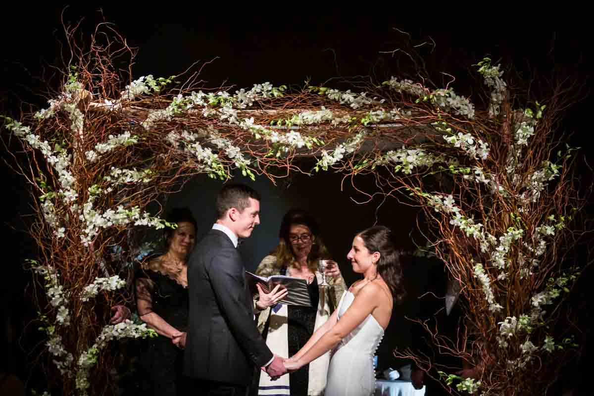 Bride and groom holding hands under chuppah at a Four Seasons Hotel New York Downtown wedding