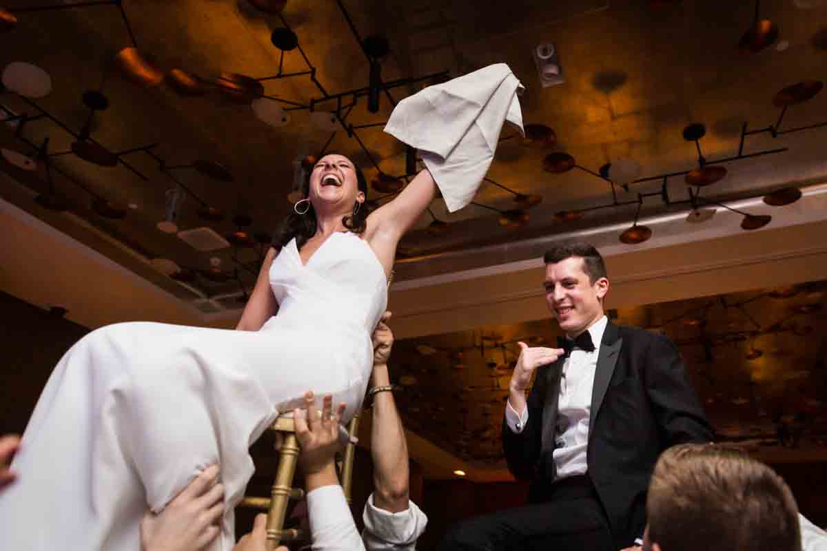 Bride and groom lifted in chairs during hora dance at a Four Seasons Hotel New York Downtown wedding