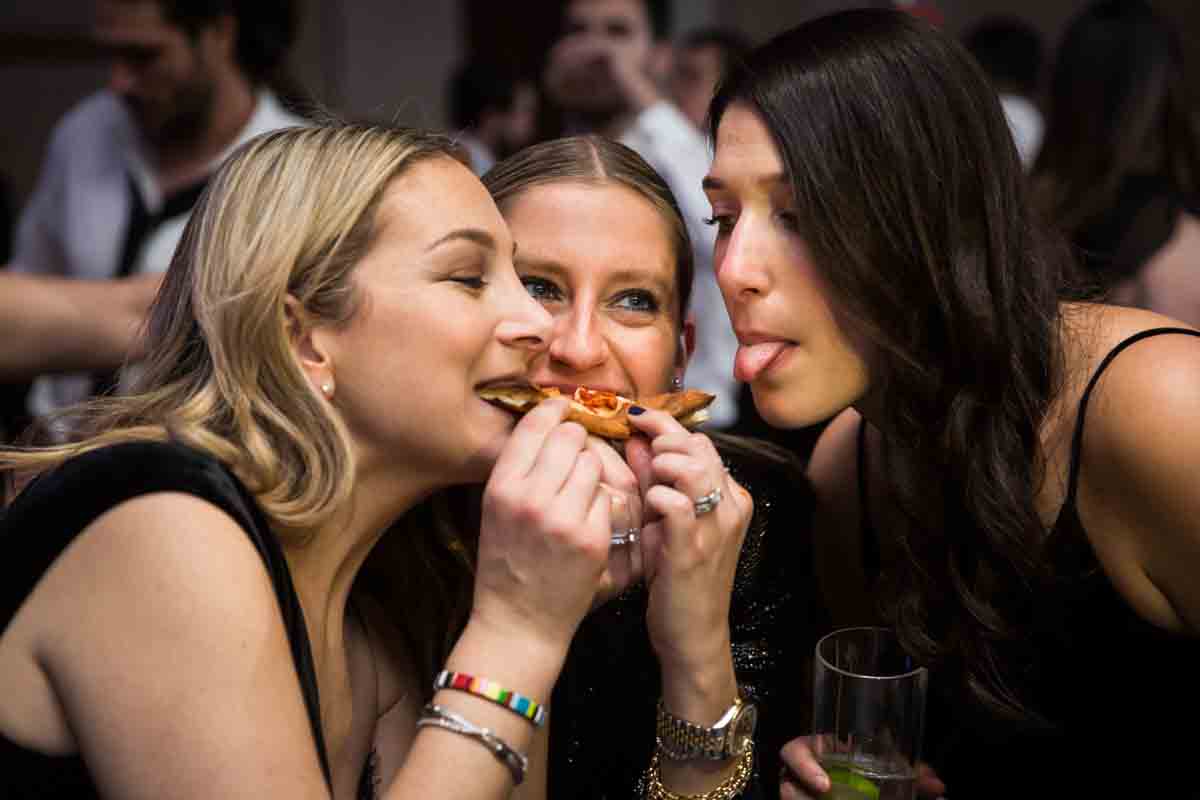 Three female guests enjoying one piece of pizza at a Four Seasons Hotel New York Downtown wedding