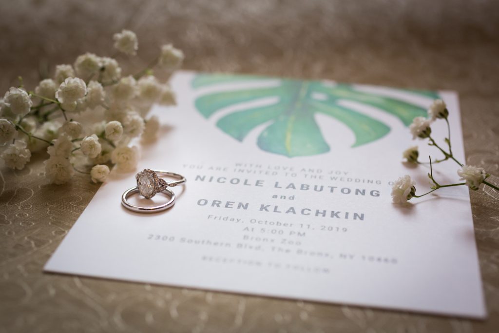 Invitation with green leaf, baby's breath, and wedding rings