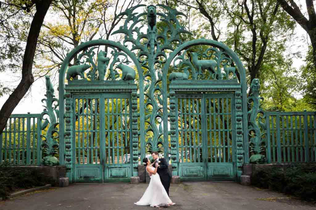 Groom dipping bride in front of Bronx Zoo gates