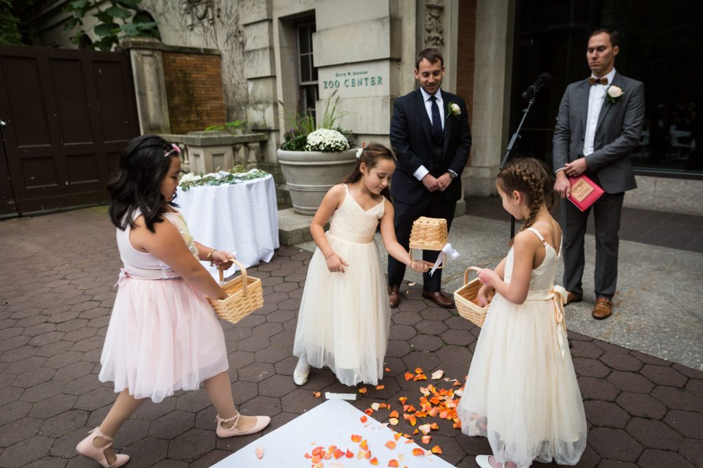 Three flower girls dumping flowers at Bronx Zoo wedding ceremony