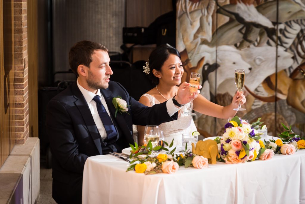 Bride and groom holding up glasses of champagne at a Bronx Zoo wedding