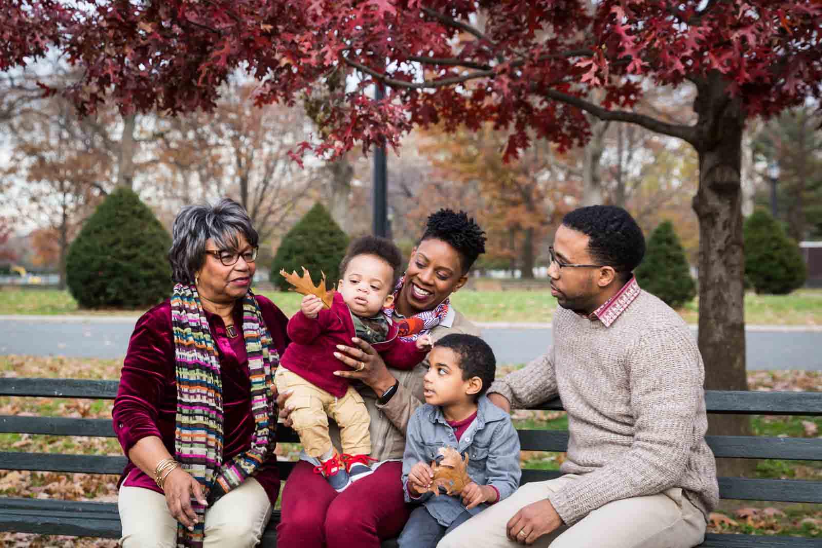 Flushing Meadows Corona Park family portrait on bench of grandmother, parents, and two children