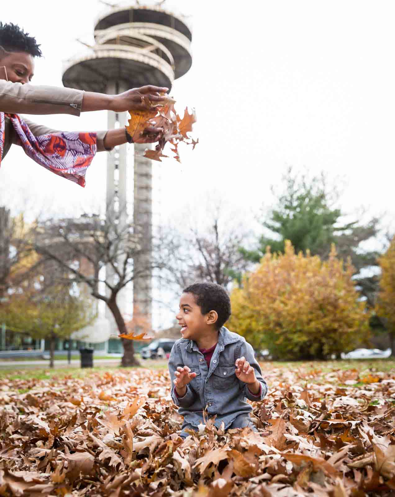 Flushing Meadows Corona Park family portrait of mother dropping leaves on little boy