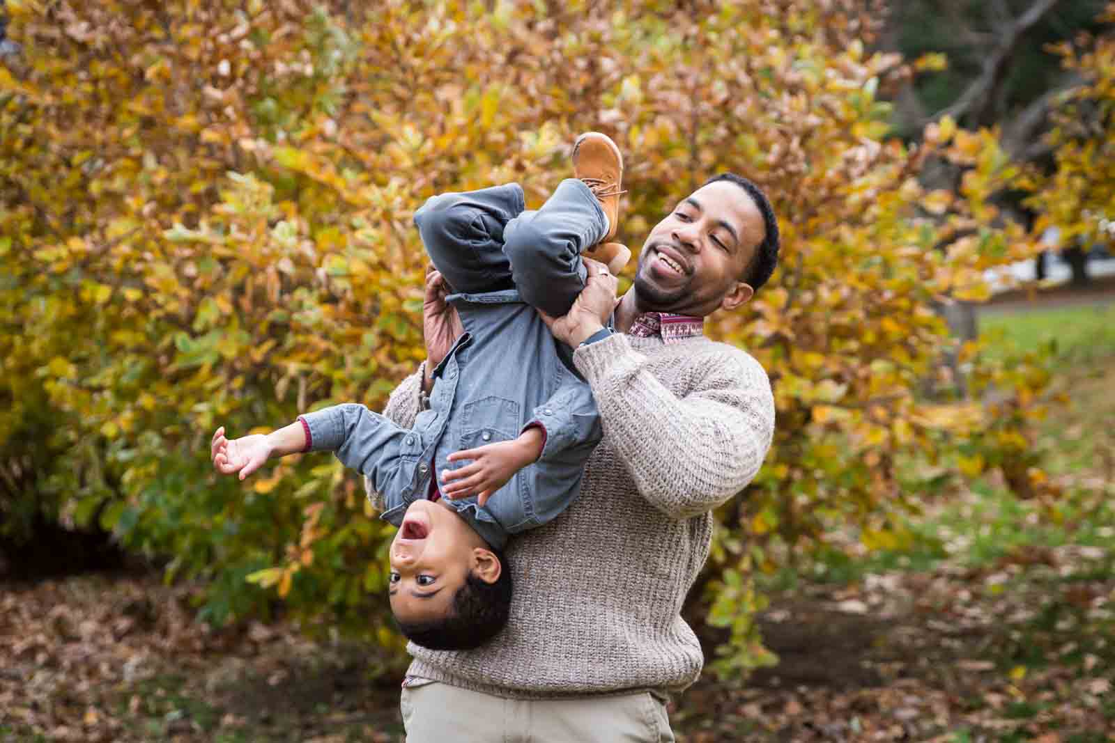 Flushing Meadows Corona Park family portrait of father holding son upside down