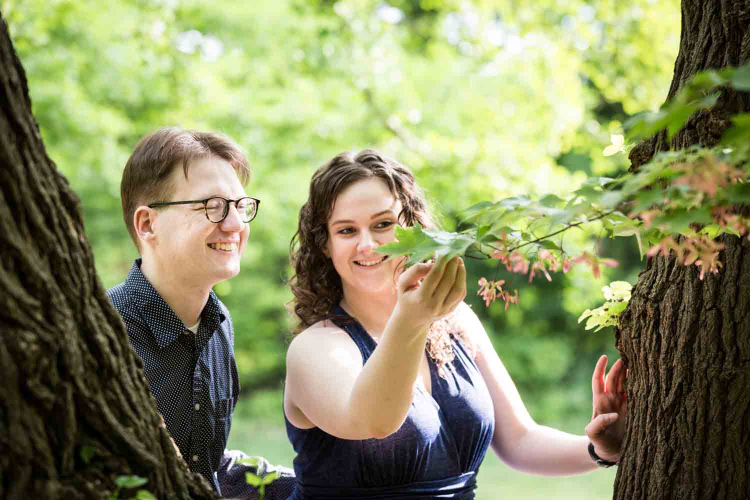 Woman showing leaves to man in Central Park Shakespeare Garden engagement photos