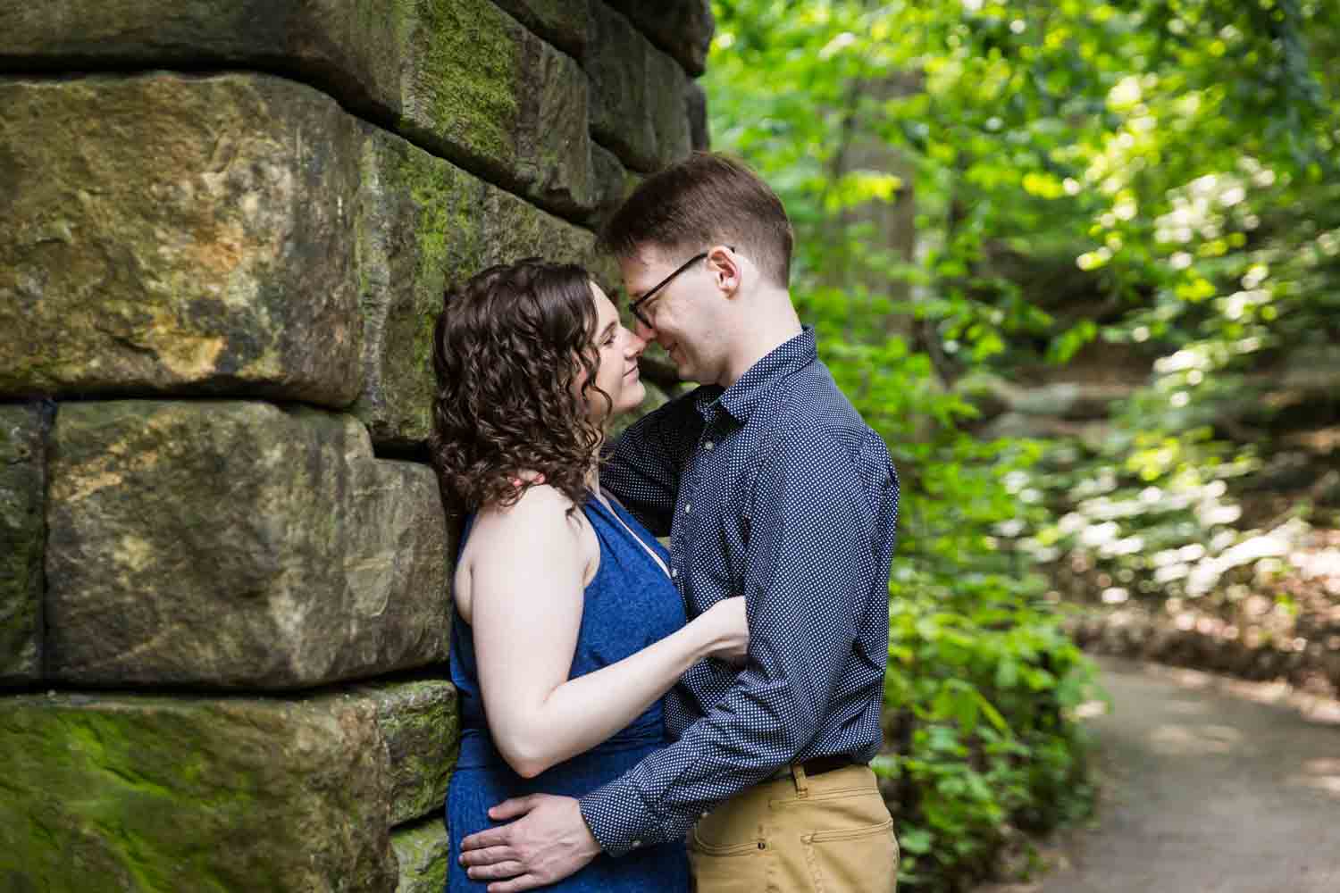 Couple leaning up against the wall of the Ramble Stone Arch