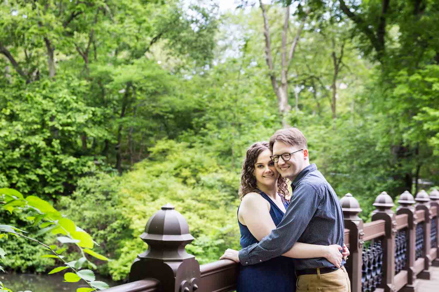Couple hugging on Oak Bridge in Shakespeare Garden engagement photos