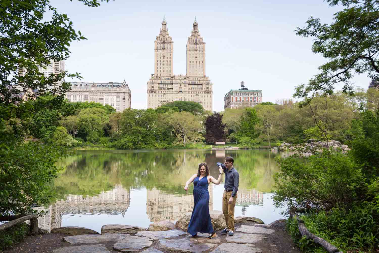 Couple dancing at Central Park lake viewing area in Shakespeare Garden engagement photos