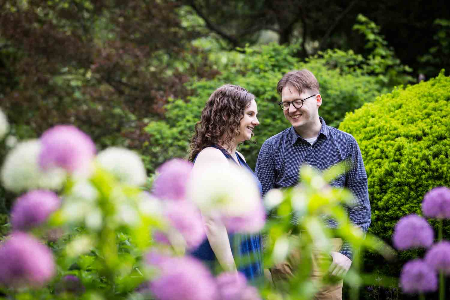 Couple walking past colorful flowers in Shakespeare Garden engagement photos